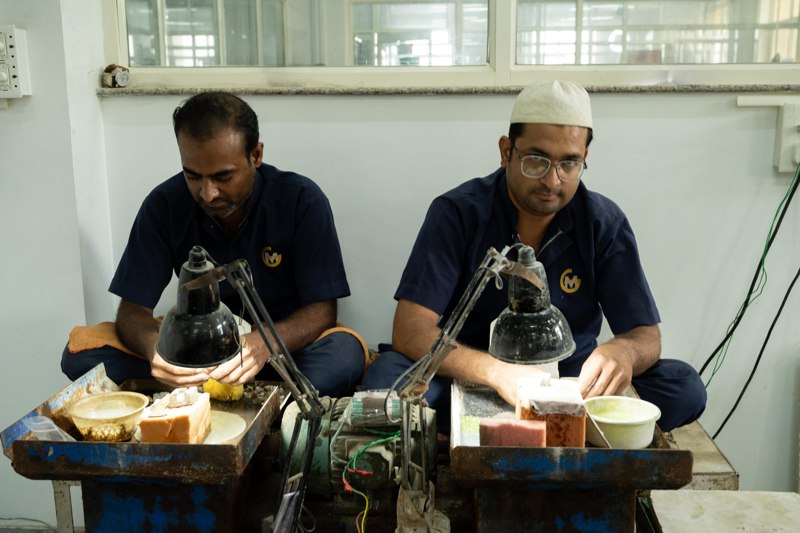 A Blazels lapidary shaping a rough gemstone at the cutting wheel
